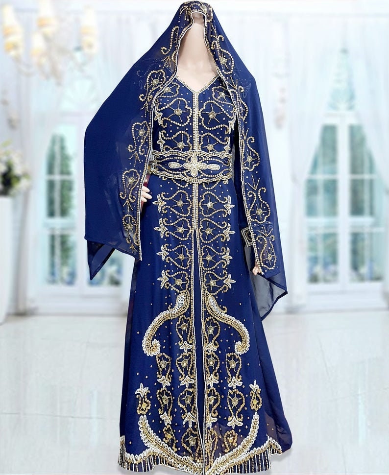 May include: A long, navy blue dress with gold embroidery and embellishments. The dress has a V-neckline and long sleeves. It is worn with a matching navy blue head scarf.