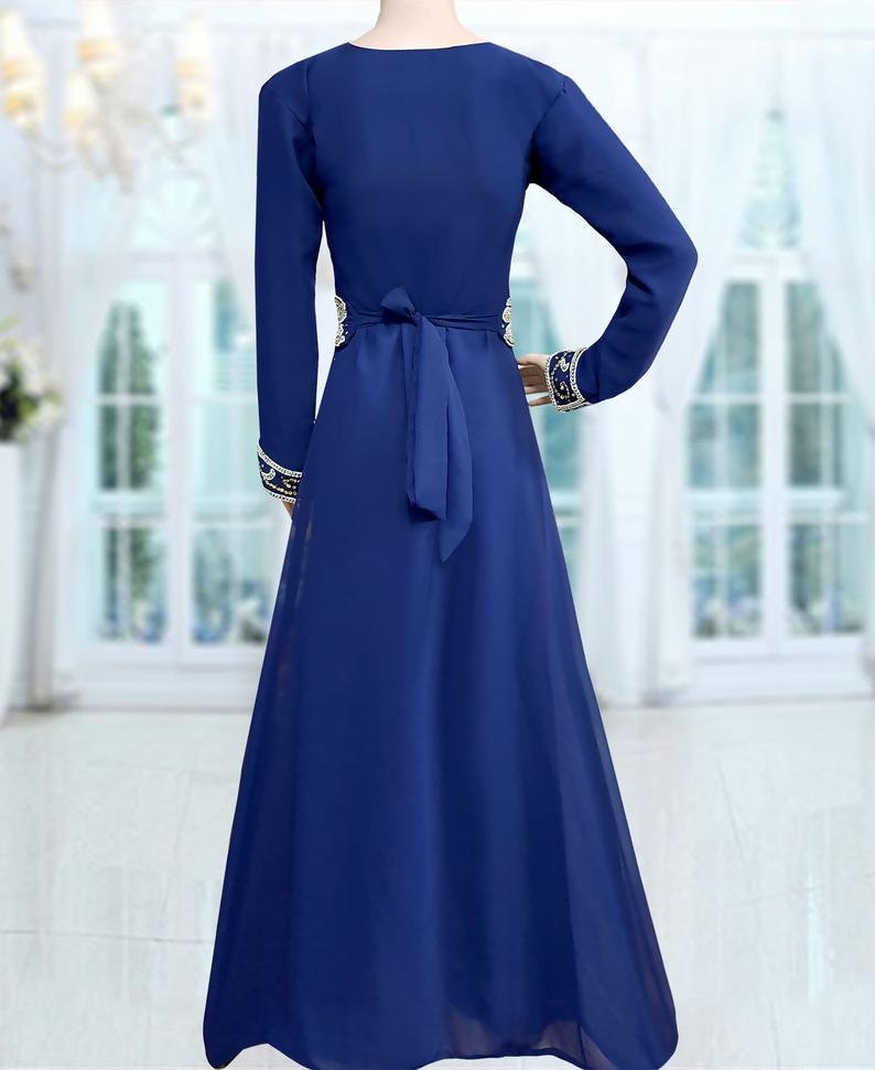 May include: A long-sleeved, royal blue maxi dress with a gold and white embroidered design around the waist and cuffs. The dress has a tie at the waist.