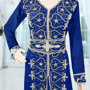 May include: A long-sleeved blue dress with gold and white embroidery and embellishments. The dress has a V-neckline and a long skirt.