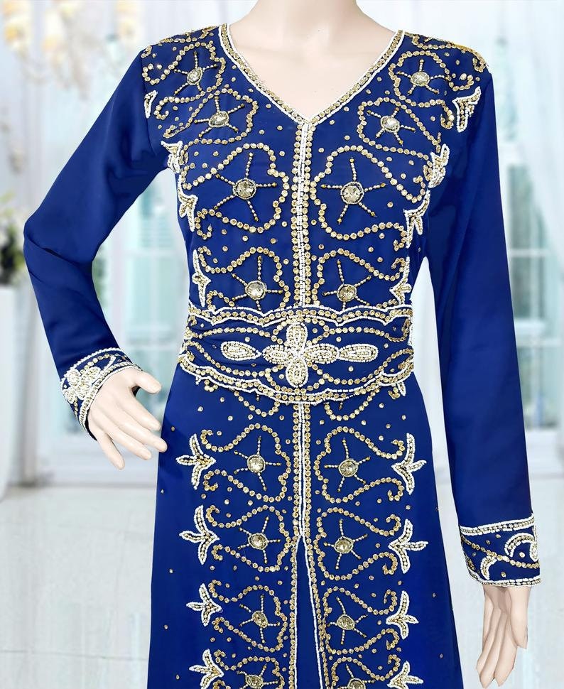May include: A long-sleeved blue dress with gold and white embroidery and embellishments. The dress has a V-neckline and a long skirt.