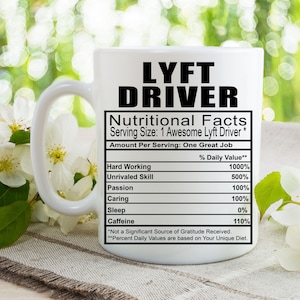 Puede incluir: Taza de café de cerámica blanca con un gráfico negro que dice "LYFT DRIVER Nutritional Facts Serving Size: 1 Awesome Lyft Driver* Amount Per Serving: One Great Job" con una tabla que enumera "Hard Working", "Unrivaled Skill", "Passion", "Caring", "Sleep" y "Caffeine" con los valores porcentuales correspondientes.