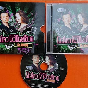 Peut inclure: Un boîtier de CD avec un fond noir et un titre rose et jaune néon qui lit "Retro Collection DJ KOGU". Le boîtier présente une photo de deux personnes avec un microphone et une table de mixage DJ.