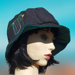 May include: A black bucket hat with a green bird embroidered on the front. The hat has a green underside.