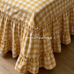 May include: A close-up of a bed skirt with a yellow and white gingham pattern. The bed skirt has a ruffled edge. The text "friendTreeHome" is visible on the fabric.