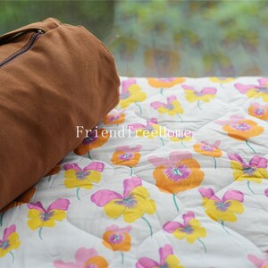 May include: A brown canvas yoga mat bag with a zipper closure, resting on a white and floral patterned fabric with the text "FriendTreeHome".