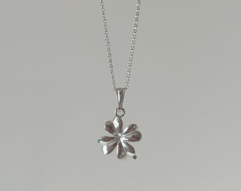 May include: A silver necklace with a four-leaf clover pendant.