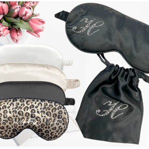 May include: Set of four sleep masks, including a black sleep mask with rhinestones, a white sleep mask, a beige sleep mask, and a leopard print sleep mask. The sleep masks are packaged in a black satin drawstring bag with rhinestones.