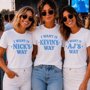 Puede incluir: Tres camisetas blancas de manga corta con texto azul. La primera camiseta dice I WANT IT NICK'S WAY con estrellas. La segunda camiseta dice I WANT IT KEVIN'S WAY con estrellas. La tercera camiseta dice I WANT IT AJ'S WAY con estrellas. Todas tienen cuello redondo.