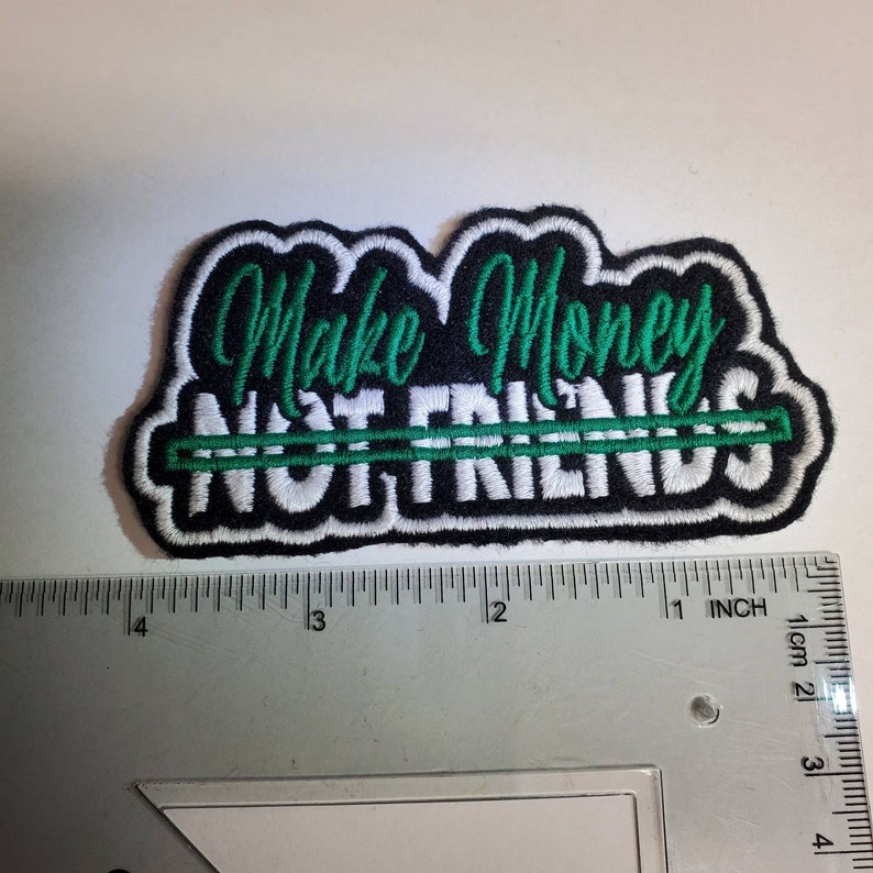May include: Black embroidered patch with white text that reads "Make Money Not Friends" with a green line through the word "Friends".