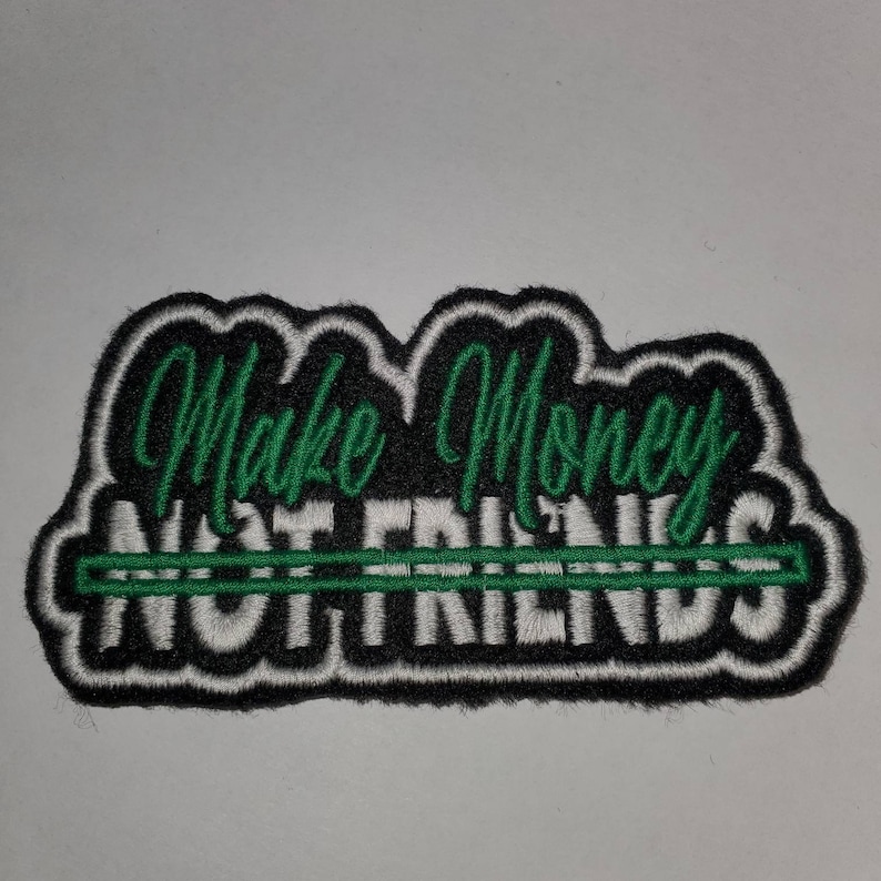 May include: Green and white embroidered patch with the text "Make Money Not Friends" with a line through the word "Friends".
