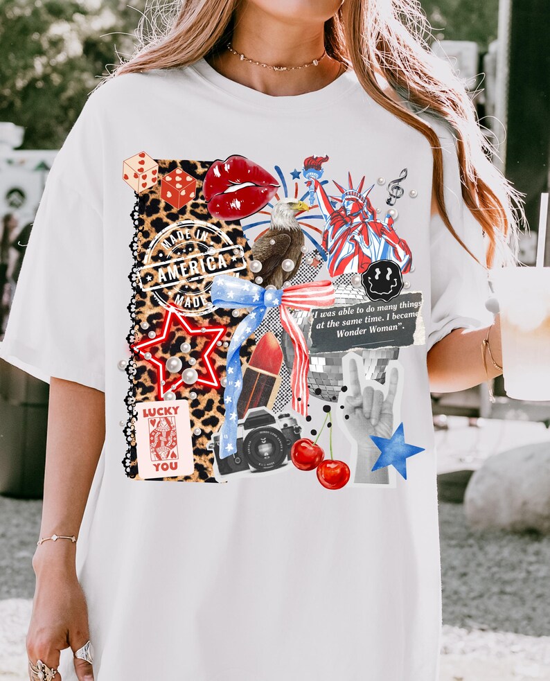 May include: White t-shirt featuring a collage of patriotic and pop culture elements. Includes a red star, dice, lips, an eagle, the Statue of Liberty, and the text "MADE IN AMERICA". Also features the text "LUCKY YOU" and "I was able to do many things at the same time, I became Wonder Woman".