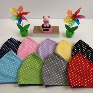 May include: Ten fabric face masks with white polka dots on a variety of colored backgrounds, including blue, pink, green, purple, gray, black, red, and yellow. The masks are arranged in a semi-circle on a white surface.