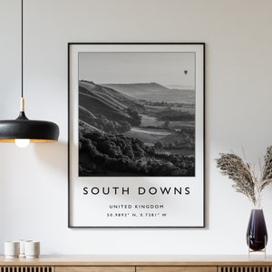 May include: Black and white photograph of rolling hills with a hot air balloon in the distance. The image is titled "South Downs, United Kingdom, 50.9893° N, 0.7381° W".