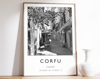 May include: Black and white photograph of a narrow street in Corfu, Greece. The street is lined with buildings and has a few tables and chairs set up outside. The text "CORFU EUROPE 39.6250° N, 19.9223° E" is printed below the image.