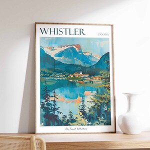 May include: A vintage travel poster featuring a scenic view of Whistler, Canada. The poster depicts a mountain range with snow-capped peaks, a lake reflecting the mountains, and a small town nestled in the valley. The text "WHISTLER" and "CANADA" is printed in a bold, sans-serif font at the top of the poster. The poster is framed in a simple wooden frame.