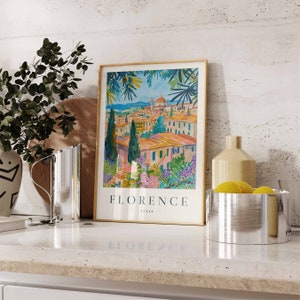 K&ouml;nnte beinhalten: Ein gerahmter Druck einer farbenfrohen Illustration von Florenz, Italien. Der Druck zeigt eine Stadtlandschaft mit Geb&auml;uden, B&auml;umen und einer Kirche. Der Text "FLORENCE ITALY" ist unter der Illustration gedruckt.