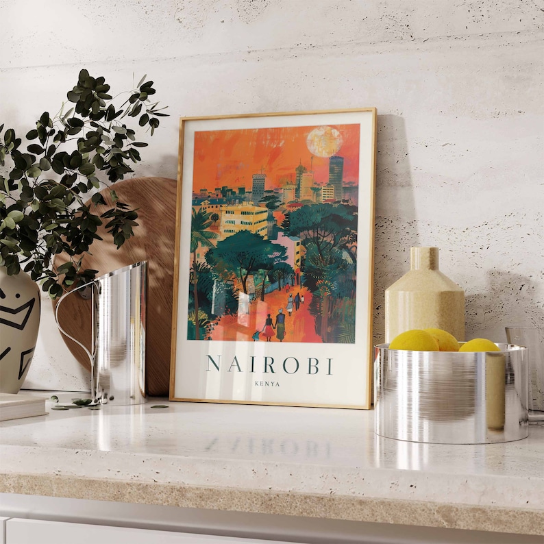 May include: A framed art print featuring a vibrant illustration of Nairobi, Kenya, with a cityscape under a sunset sky. The print includes the city's name and country. The artwork is displayed on a countertop with decorative items.