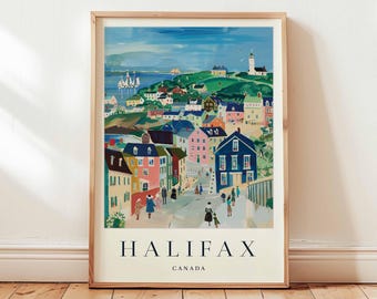 Op de afbeelding: Een ingelijste kunstdruk van Halifax, Canada, met een kleurrijke illustratie van een kustplaats. Het kunstwerk toont gebouwen in roze, blauw en geel, met een vuurtoren en zeilboten op de achtergrond. De woorden "HALIFAX" en "CANADA" staan onderaan afgedrukt.