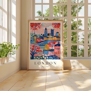 Peut inclure: Une illustration color&eacute;e de Londres, en Angleterre, avec un ciel rose et une ville avec des b&acirc;timents, des arbres et une rivi&egrave;re. Le texte "LONDON ENGLAND" est en bas de l'image.