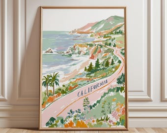 May include: A framed art print depicting a coastal California landscape. The artwork features a pink road with the word "CALIFORNIA" and a winding path along the coast. The scene includes palm trees, ocean waves, and colorful hills.