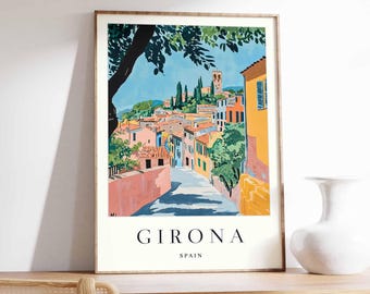 May include: A colorful illustration of a street scene in Girona, Spain. The image features a winding street lined with colorful buildings, a church tower in the distance, and a lush green tree canopy overhead. The text "GIRONA SPAIN" is printed below the image.