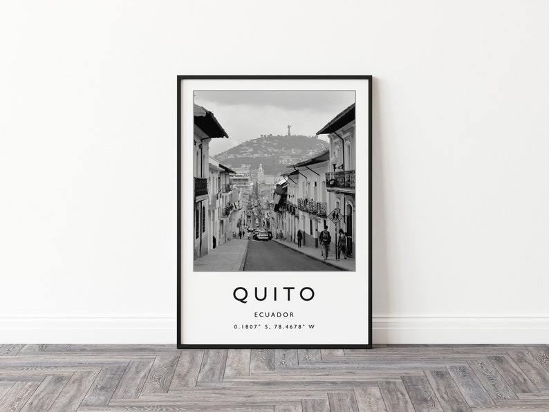 May include: Black and white photograph of a street in Quito, Ecuador. The street is lined with buildings and there are people walking on the sidewalk. The text "QUITO" is printed below the image, along with the coordinates "0.1807&deg; S, 78.4678&deg; W".