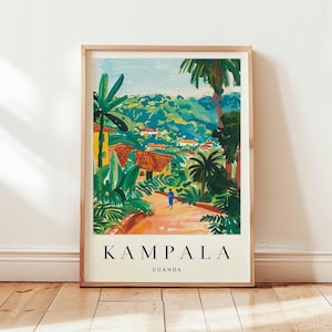 Op de afbeelding: Een ingelijste kunstdruk met een kleurrijk landschap van Kampala, Oeganda. Het kunstwerk toont een pad dat door weelderig groen, palmbomen en gebouwen met rode daken leidt. Het woord "KAMPALA" is gedrukt in vette zwarte letters, met "UGANDA" eronder.
