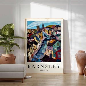 Puede incluir: Un p&oacute;ster enmarcado con una colorida ilustraci&oacute;n de Barnsley, Inglaterra. La obra de arte representa una escena callejera con edificios de varios colores, una torre de iglesia y el nombre de la ciudad en letras negritas.