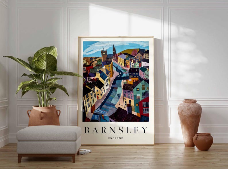 Puede incluir: Un p&oacute;ster enmarcado con una colorida ilustraci&oacute;n de Barnsley, Inglaterra. La obra de arte representa una escena callejera con edificios de varios colores, una torre de iglesia y el nombre de la ciudad en letras negritas.