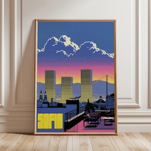 May include: A framed art print featuring a stylized cityscape of Sofia at sunset. The image displays three tall rectangular buildings against a gradient sky with clouds, a rooftop terrace with chairs and a table, and the word SOFIA in yellow.