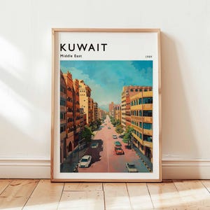 May include: A framed art print showing a street scene in Kuwait, Middle East, from 1989. The artwork depicts a wide avenue lined with buildings in shades of orange and yellow, with cars on the road under a blue sky.
