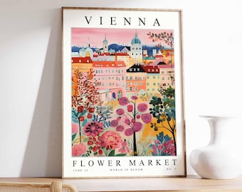 May include: A framed art print depicting Vienna's Flower Market. The illustration shows a colourful cityscape with buildings and a flower garden. The print includes the text "VIENNA" at the top, and "FLOWER MARKET, JUNE 15, WORLD IN BLOOM, NO. 7" at the bottom.
