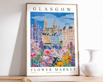 May include: A framed art print featuring a colorful illustration of Glasgow, Scotland. The artwork depicts buildings, a river, and a vibrant flower market. Text at the top reads "GLASGOW" and at the bottom "FLOWER MARKET" with "JUNE 15" and "WORLD IN BLOOM".