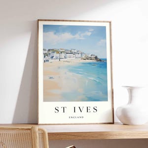 May include: A watercolor painting of a coastal town with white buildings and a sandy beach. The water is blue and there are waves crashing on the shore. The text "ST IVES ENGLAND" is printed at the bottom of the painting.