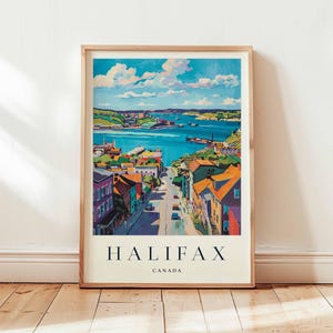 May include: A framed art print of Halifax, Canada, featuring a colorful illustration of the city's harbor and buildings. The artwork has a vintage travel poster style, with the word "HALIFAX" and "CANADA" printed at the bottom.