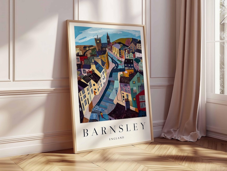 Puede incluir: Una impresi&oacute;n art&iacute;stica enmarcada que muestra una representaci&oacute;n colorida y estilizada de Barnsley, Inglaterra. La obra de arte presenta edificios de varios colores, con el nombre de la ciudad, BARNSLEY, y el pa&iacute;s, ENGLAND, impresos en la parte inferior. La impresi&oacute;n se exhibe contra una pared blanca y un suelo de madera.