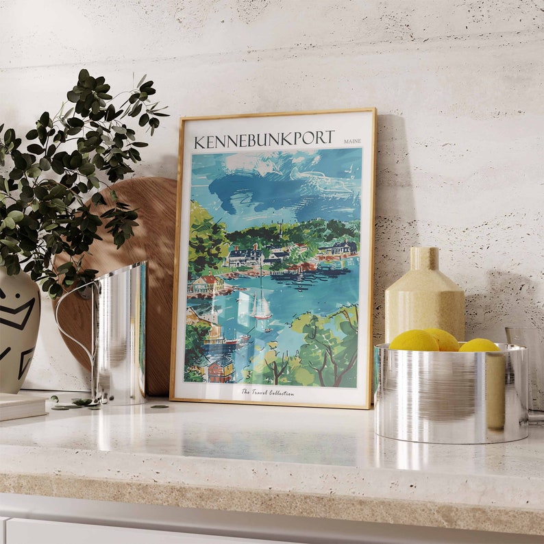 May include: A framed travel poster of Kennebunkport, Maine, with a gold frame. The poster depicts a coastal town with boats, trees, and buildings. The text "The Travel Collection" is at the bottom.