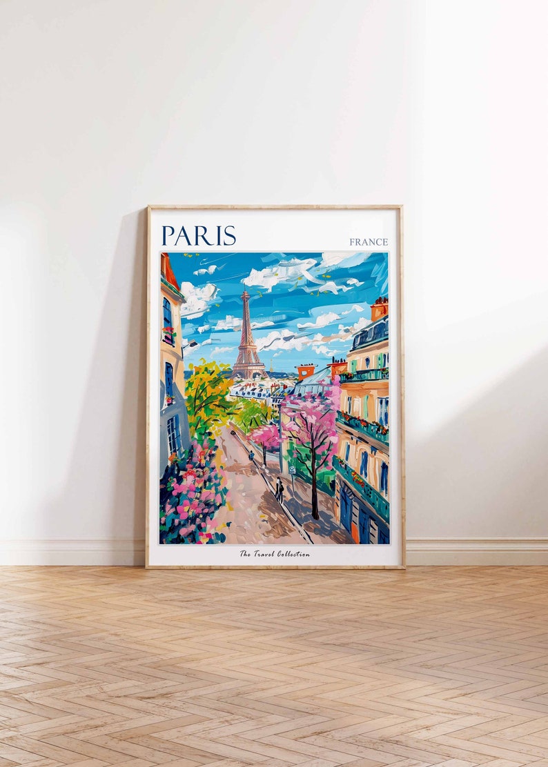 May include: A colorful painting of a Parisian street scene with the Eiffel Tower in the background. The painting features a street lined with buildings, trees, and flowers. The text "PARIS" and "FRANCE" are at the top of the painting, and the text "The Travel Collection" is at the bottom.
