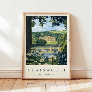 Op de afbeelding: Een ingelijste kunstafdruk met een schilderachtig uitzicht op Chatsworth House in het Peak District. Het kunstwerk toont een statig huis, een brug over een rivier en weelderig groen onder een blauwe lucht. De print zit in een houten lijst.