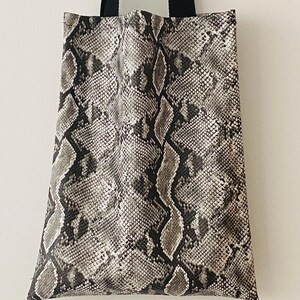 May include: A black and white snakeskin tote bag with black straps.