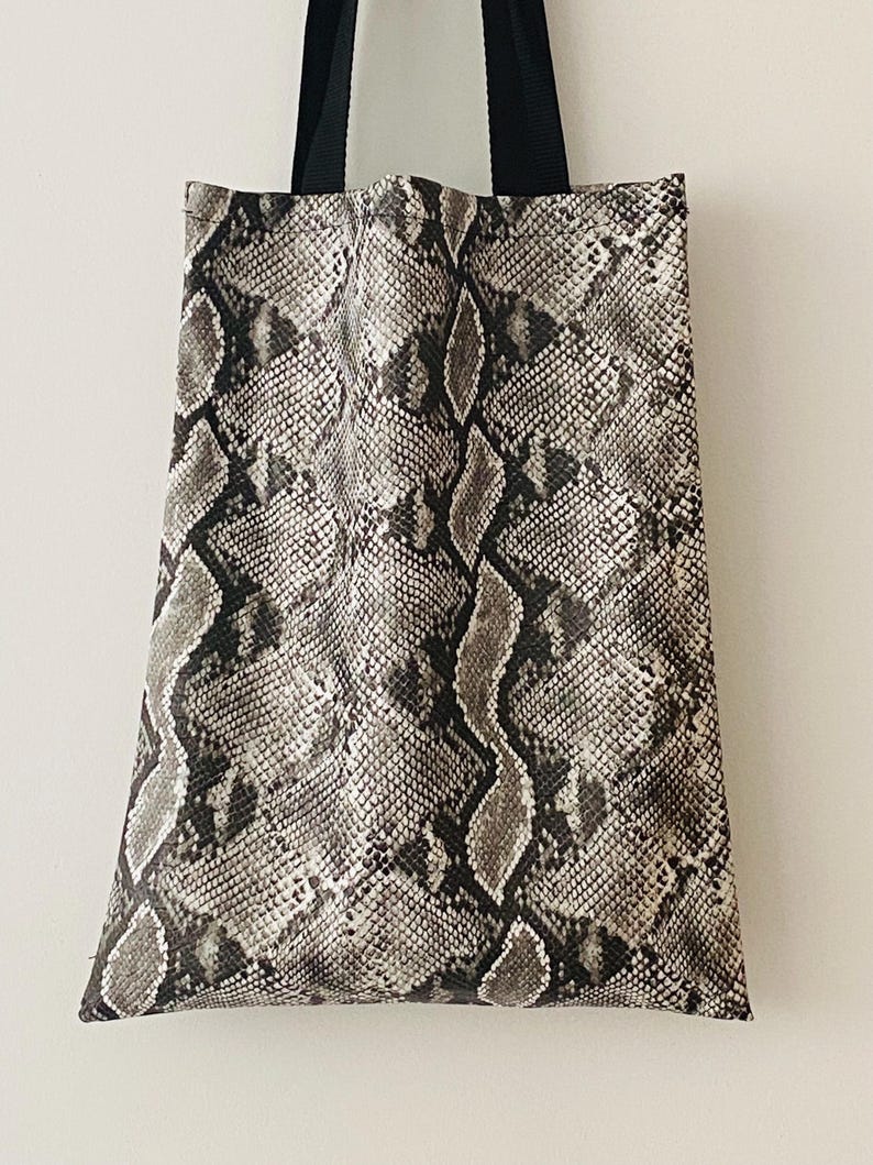 May include: A black and white snakeskin tote bag with black straps.