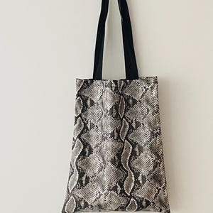 May include: A black and white snakeskin tote bag with black straps.
