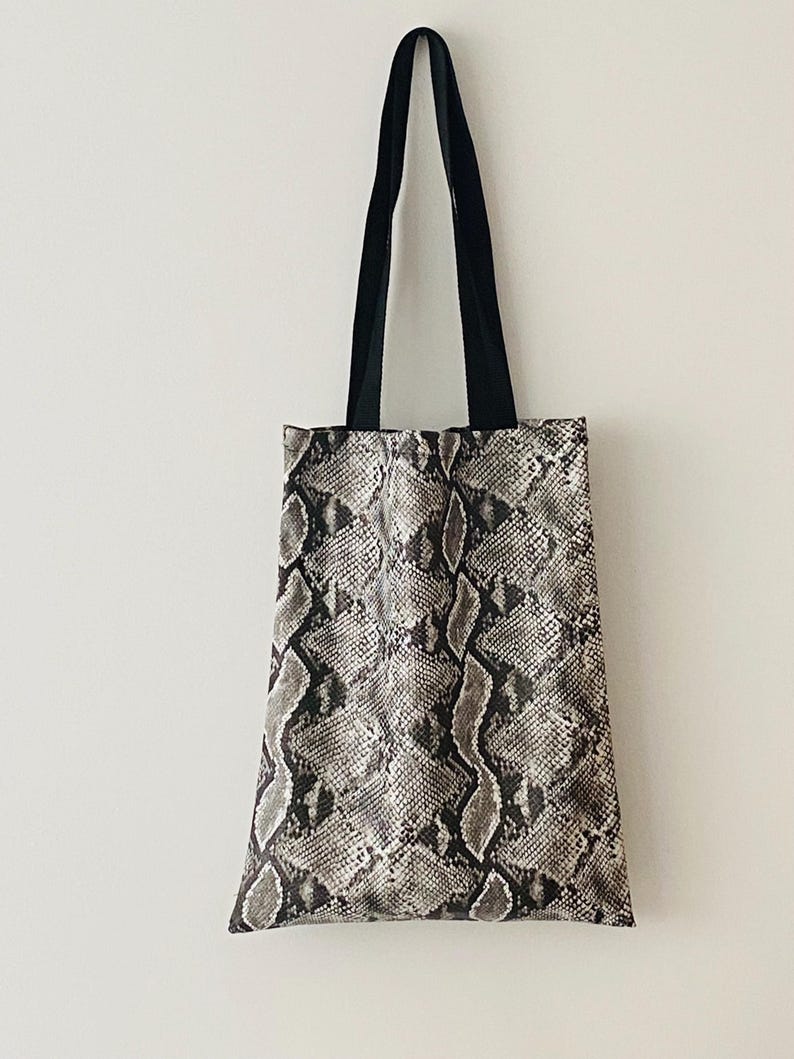 May include: A black and white snakeskin tote bag with black straps.