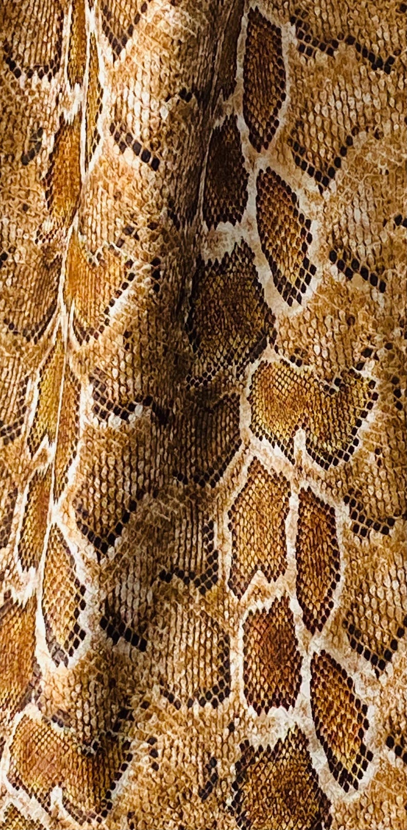 May include: Close-up of a brown and tan snakeskin pattern. The pattern is made up of small, overlapping scales.