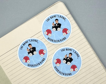 May include: Three round stickers with a blue background and a white outline. Each sticker features a cartoon image of James Bond holding a gun and standing in a pool of water with red oxygen atoms. The text on each sticker reads "THE NAME'S BOND," and "HYDROGEN BOND".