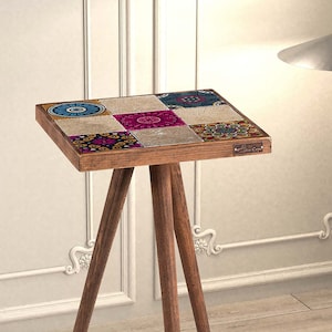 May include: A small wooden side table with a square top featuring a colourful mosaic tile design. The table has three legs and is made of dark wood.