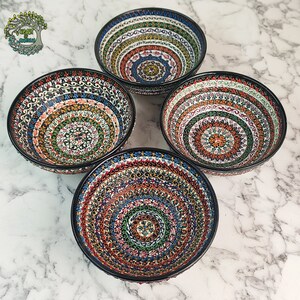 May include: Four ceramic bowls with intricate, colorful patterns. Each bowl features a black rim and a detailed design in shades of blue, orange, green, and red. The bowls are arranged in a square formation, showcasing their decorative appeal.