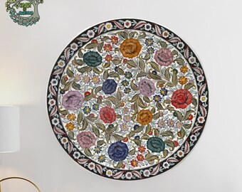 Puede incluir: Una decoración mural redonda con un diseño floral y un borde negro. El diseño presenta una variedad de flores coloridas, incluyendo rojas, moradas y azules, sobre un fondo blanco. La obra de arte está montada en una pared blanca.
