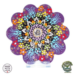 May include: A purple, flower-shaped ceramic coaster with a detailed floral design. The coaster has a central mandala pattern surrounded by dots and swirls in various colours. The words "MADE WITH LOVE" are printed on the bottom left.