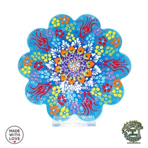 Könnte beinhalten: Ein handbemalter Keramikuntersetzer mit floralem Design. Der Untersetzer hat einen hellblauen Hintergrund mit einem farbenfrohen, komplizierten Muster aus orangefarbenen, violetten, gelben und roten Details. Der Text "MADE WITH LOVE" ist sichtbar.